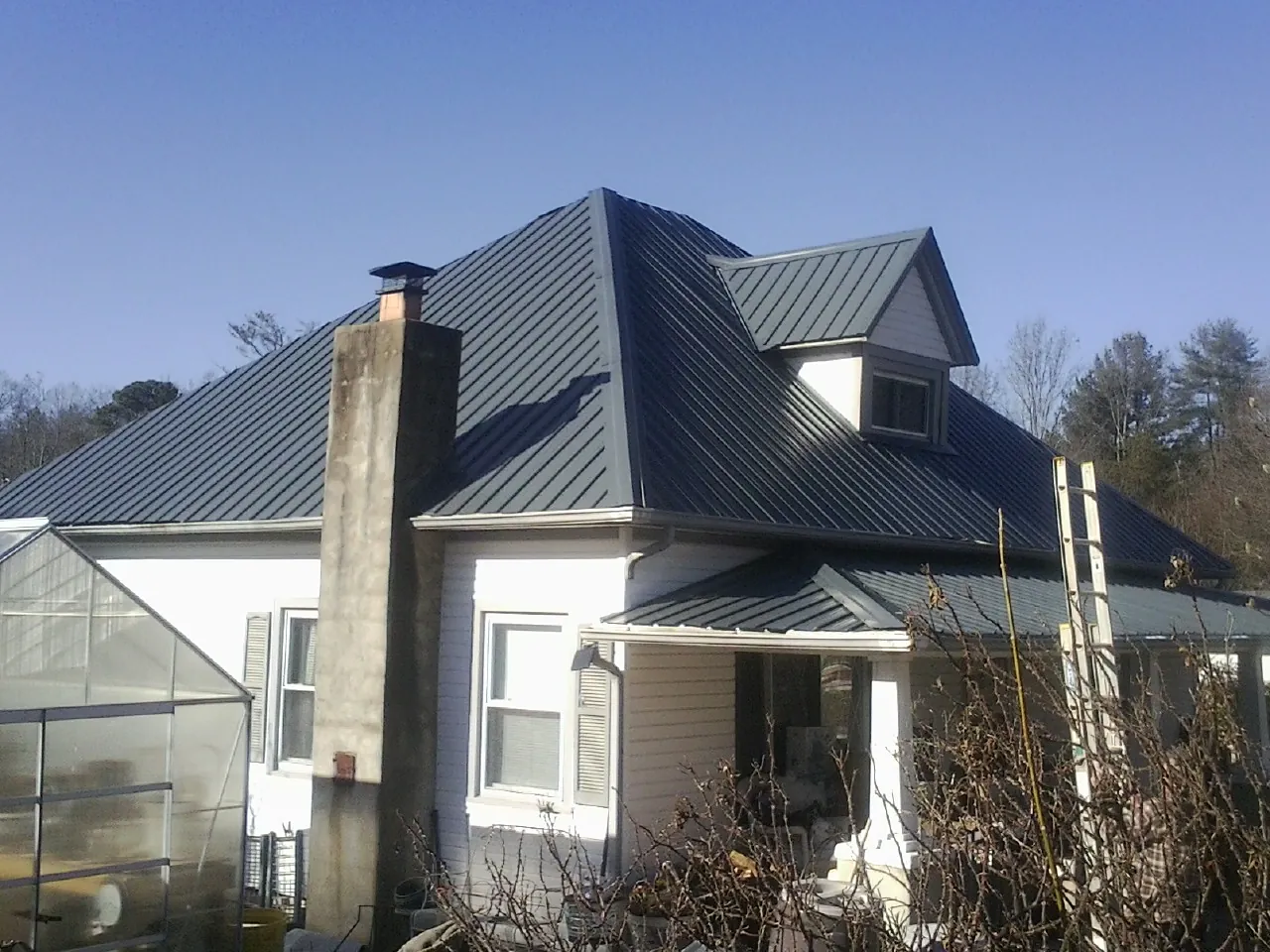 Dark blue standing seam metal roof on a white farmhouse with dormer — Slate & Tile Roof Repair by Roofing Brothers in Neffs