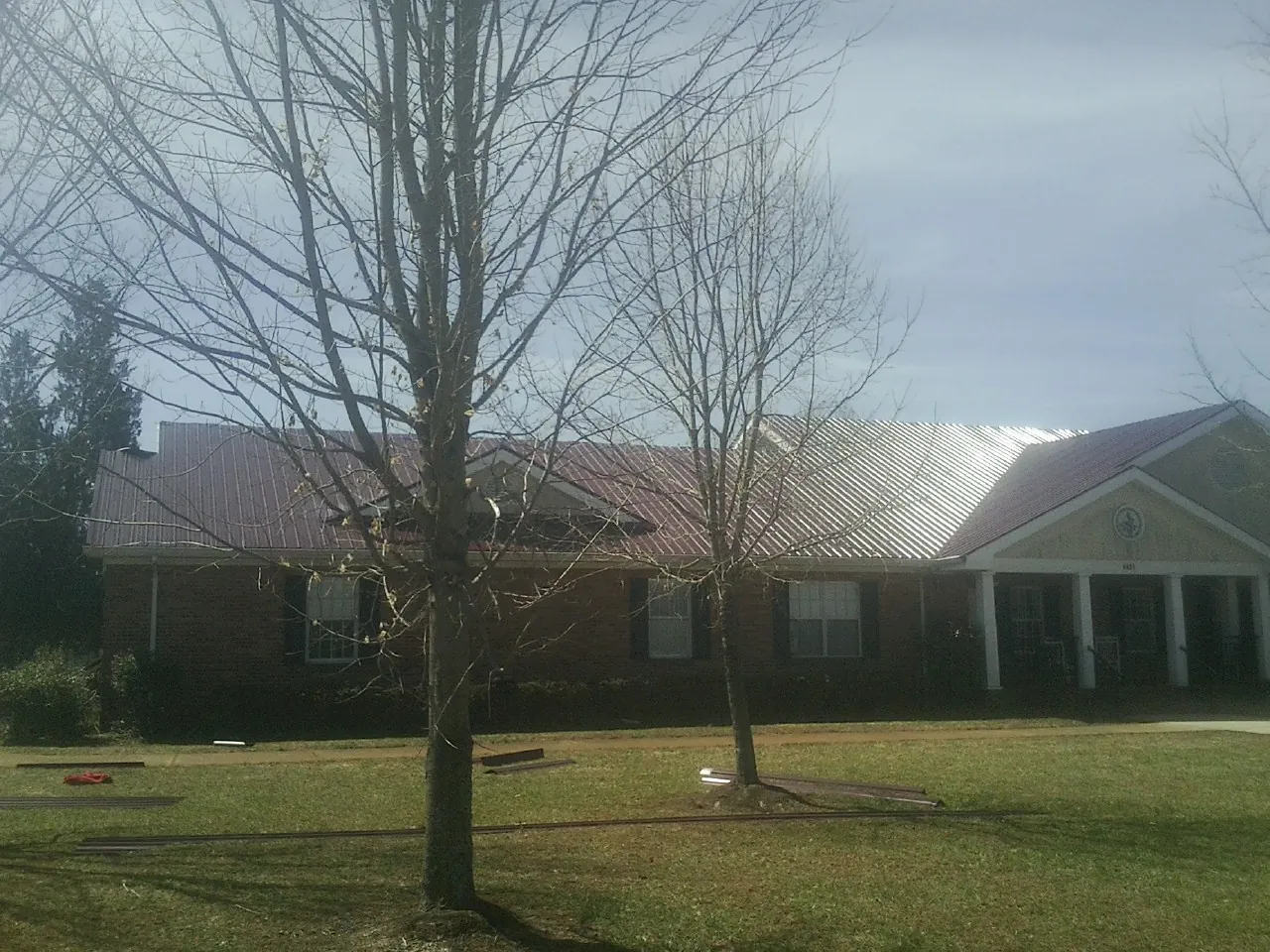Red metal roof on a brick building seen from the front lawn in Neffs