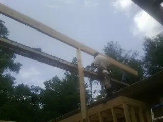 Carpenter setting a ridge beam over a new addition frame — Ice Dam Removal by Roofing Brothers in Neffs
