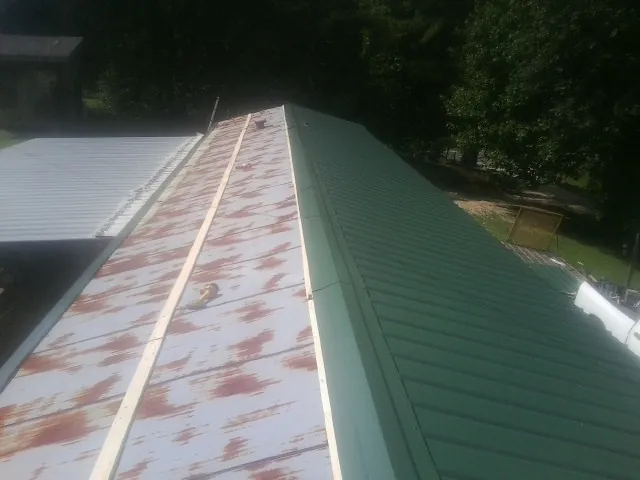 Old rusted panels beside newly installed green metal roofing — Wind Damage Roof Repair by Roofing Brothers in Neffs