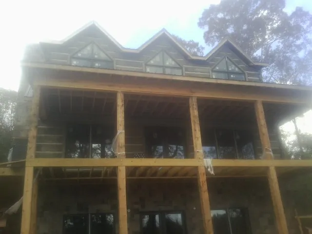 Dormers and porch framing on a large log home under construction — Roof Coating work by our crew in Neffs