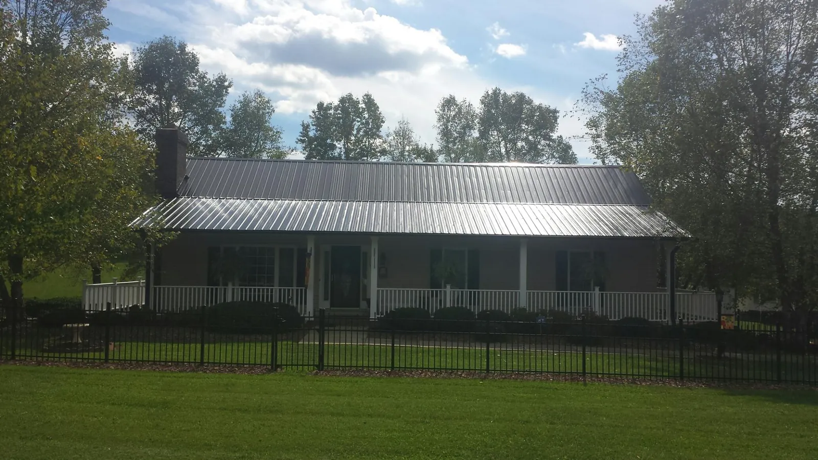 Gray metal roof on a brick ranch with a full width front porch — Gutter Guard Installation work by our crew in Neffs