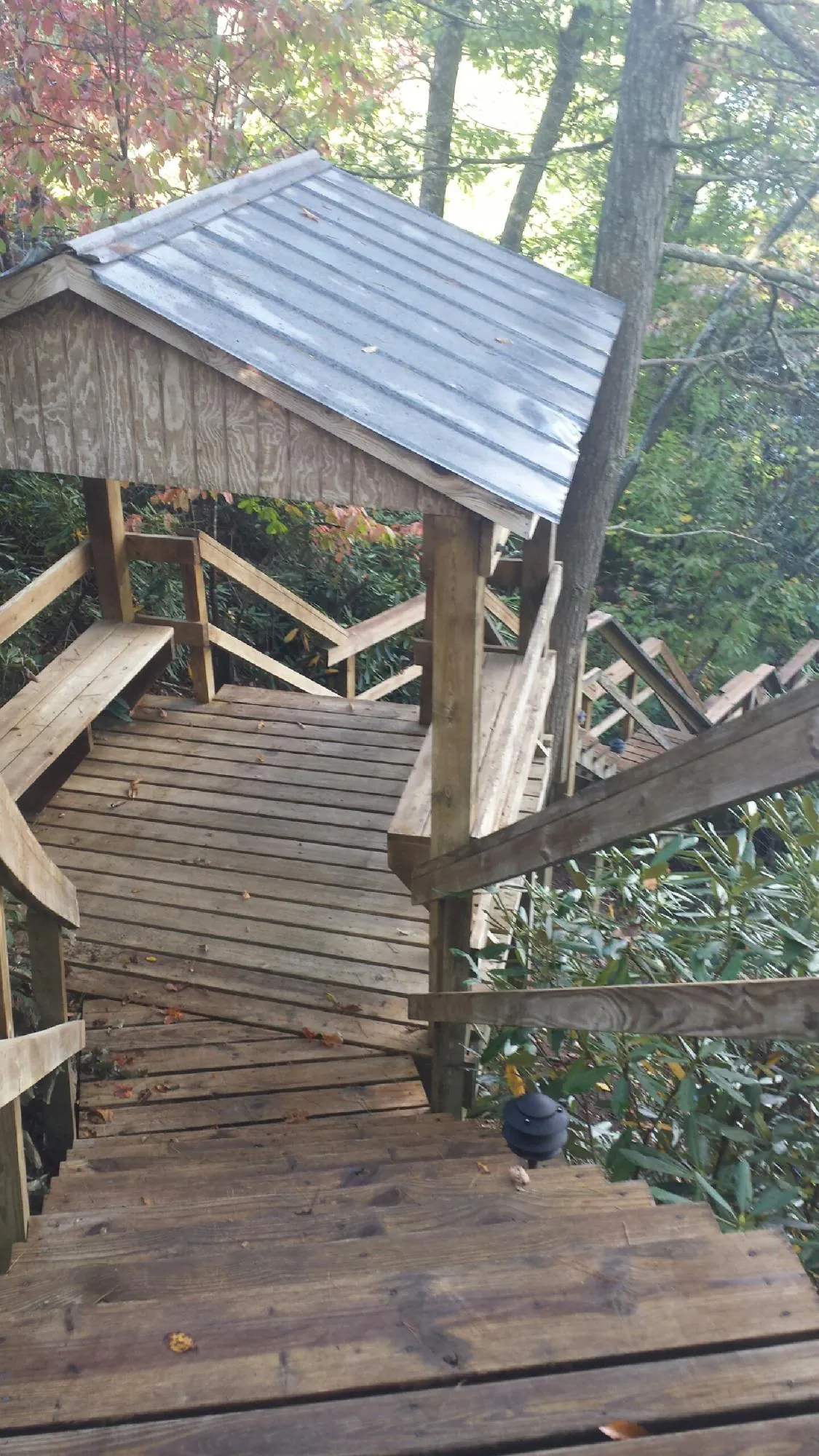 Metal roofed shelter over wooden steps on a wooded walkway — Skylight Repair & Installation work by our crew in Neffs