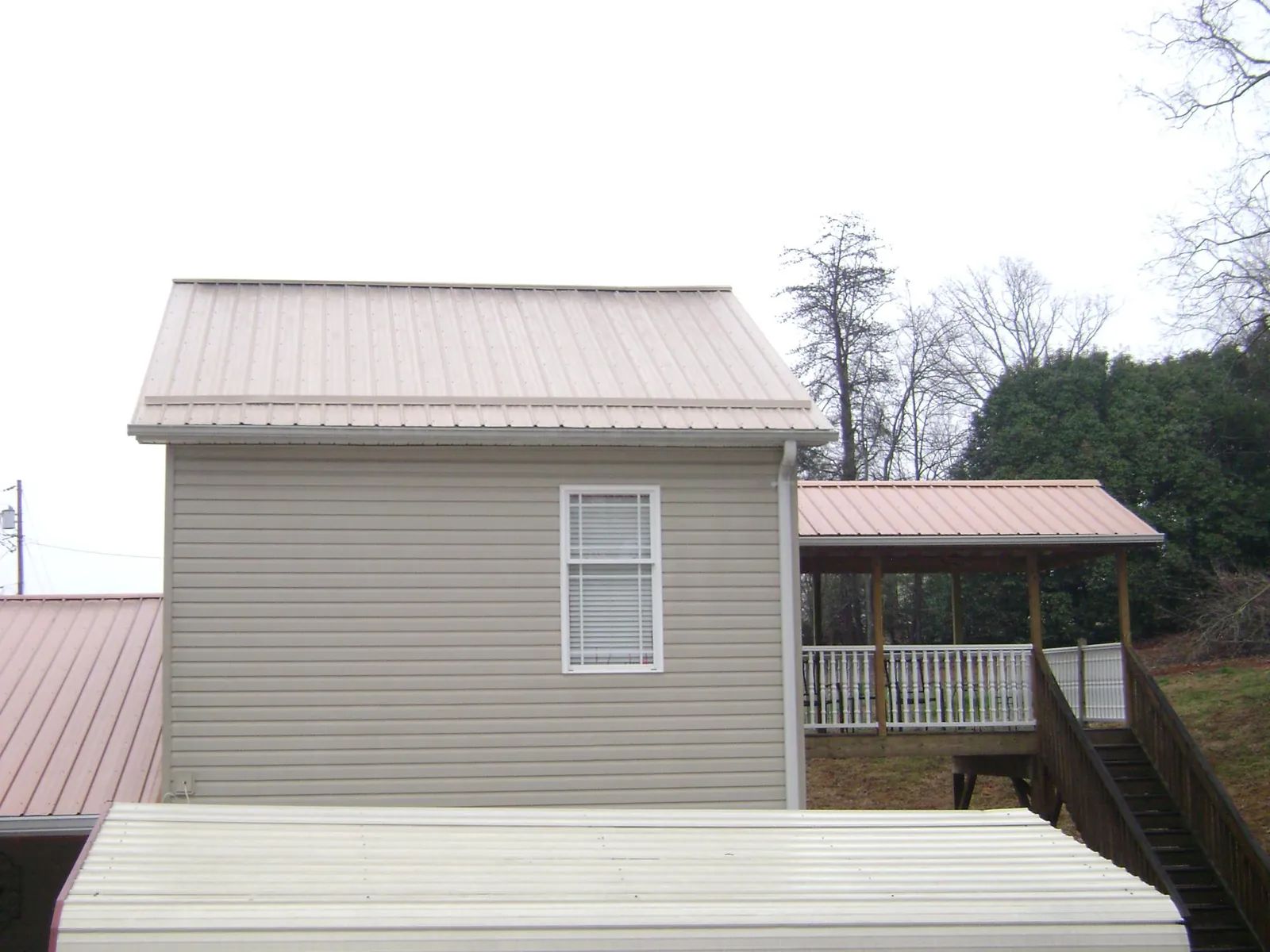 Tan metal roofs on a two story addition and attached porch, from a Roof Replacement job in Neffs
