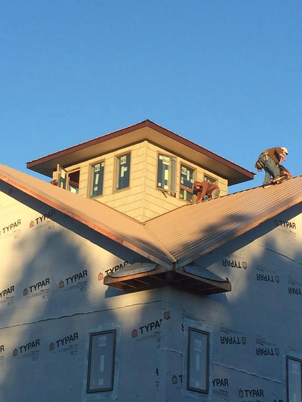 Roofers working around a rooftop cupola on a new metal roof at sunset — Roof Waterproofing in Neffs by Roofing Brothers